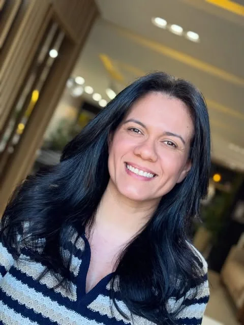 Cliente sorrindo no studio SoHo, com ripado de madeira e luzes quentes ao fundo